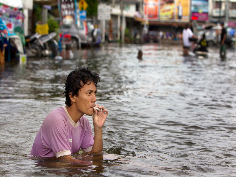 man-smokes-cigarette-flooded-street-ayutthaya-floods.jpg.996a6e16205af463da58d9f28aae4c34.jpg