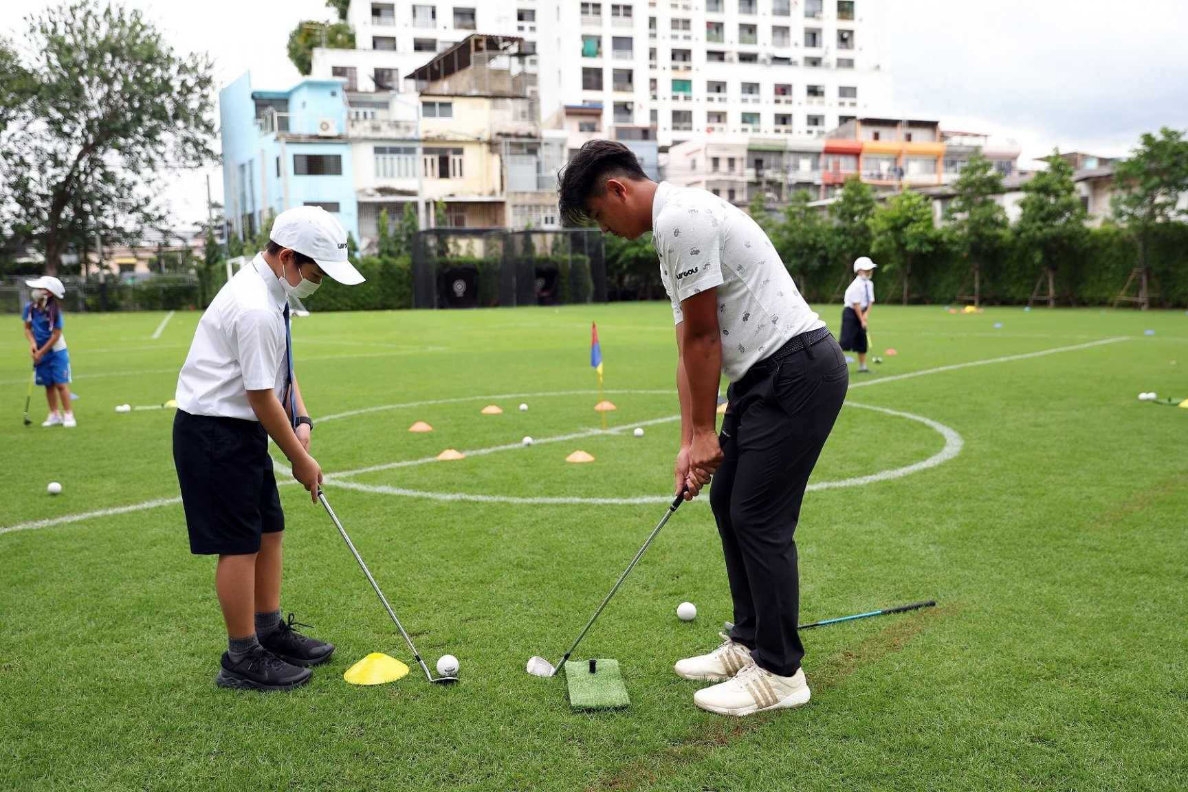 LIV Golf Invitational Bangkok ambassador TK guides a pupil through his swing.JPG