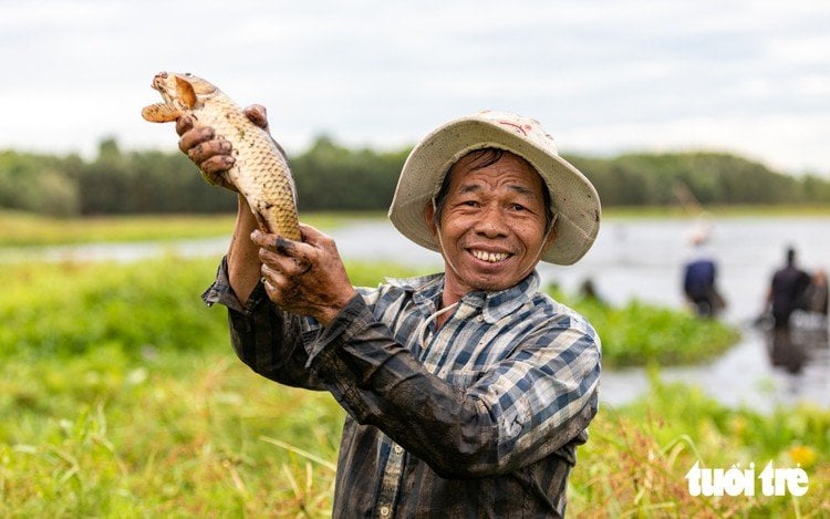A farmer holds a large fish caught at the Tra Loc wetland festival